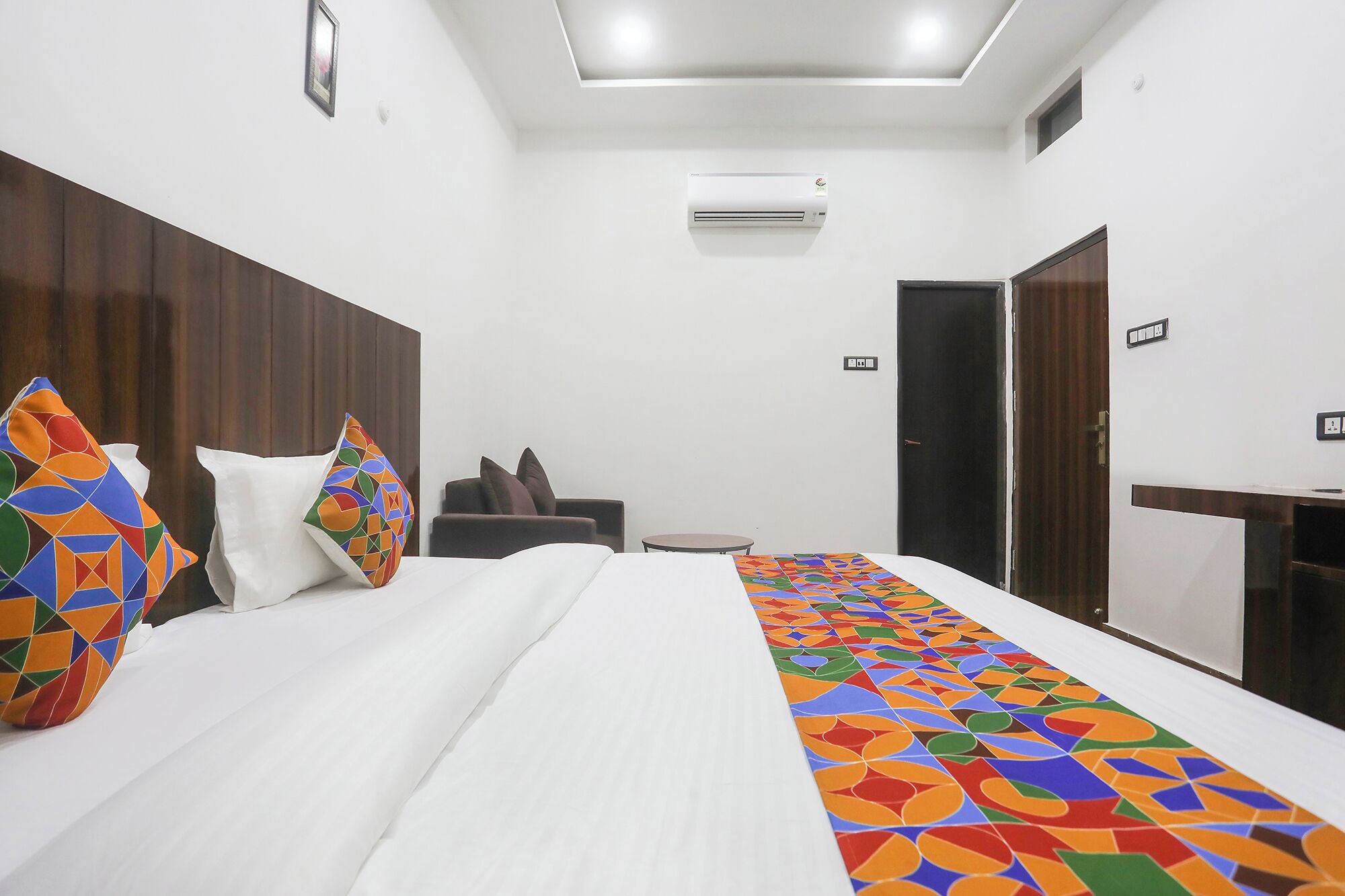 A hotel room with a bed, a desk, a chair, and a wardrobe.