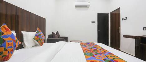 A hotel room with a bed, a desk, a chair, and a wardrobe.