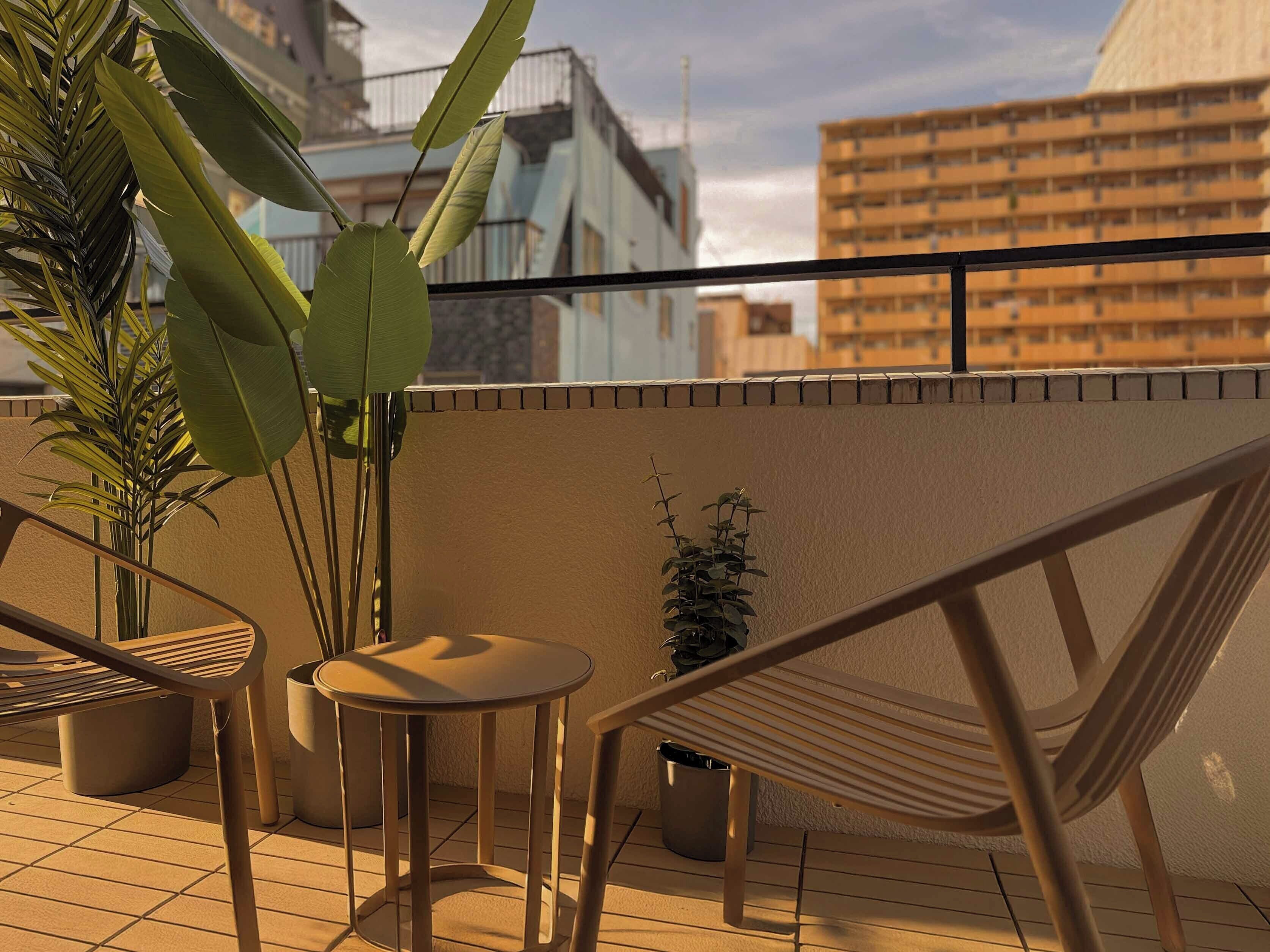 A rooftop terrace with a hammock, a round table, and potted plants.