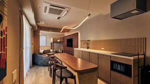 A modern kitchen with a long countertop, wooden cabinets, and a built-in stove. - illi Mia Kinshicho (Tokyo)