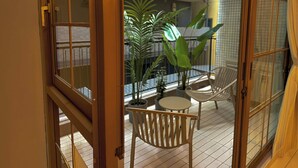 A balcony with a view of a building, potted plants, and two white chairs. - illi Mia Kinshicho (Tokyo)