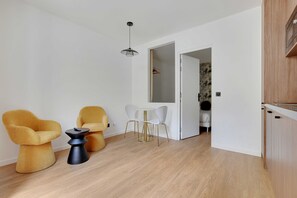Een moderne woonkamer met een eethoek, met een bank, een bijzettafeltje en een hanglamp.