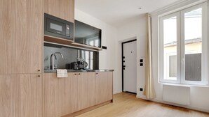 A modern kitchen with wooden cabinets, a built-in microwave, and a coffee machine. - Charming Apartment - 1BR - 2P - Montreuil (Montreuil)