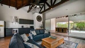 Un salon moderne avec un canapé, une table basse et une vue sur la cuisine et l’espace extérieur.