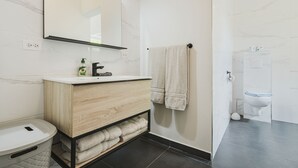 Une salle de bain moderne avec un mur en marbre, un meuble-lavabo en bois, des toilettes et un porte-serviettes.
