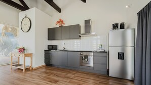 A modern kitchen with grey cabinets, a stainless steel refrigerator, and a wooden floor. - Picaron Villas (Santa Cruz)