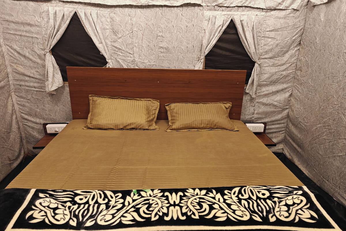 A bed with a wooden headboard, two pillows, and a patterned bedspread.