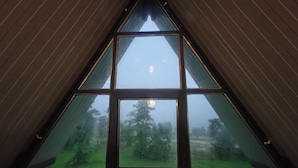 Una ventana triangular con vistas a un paisaje verde.