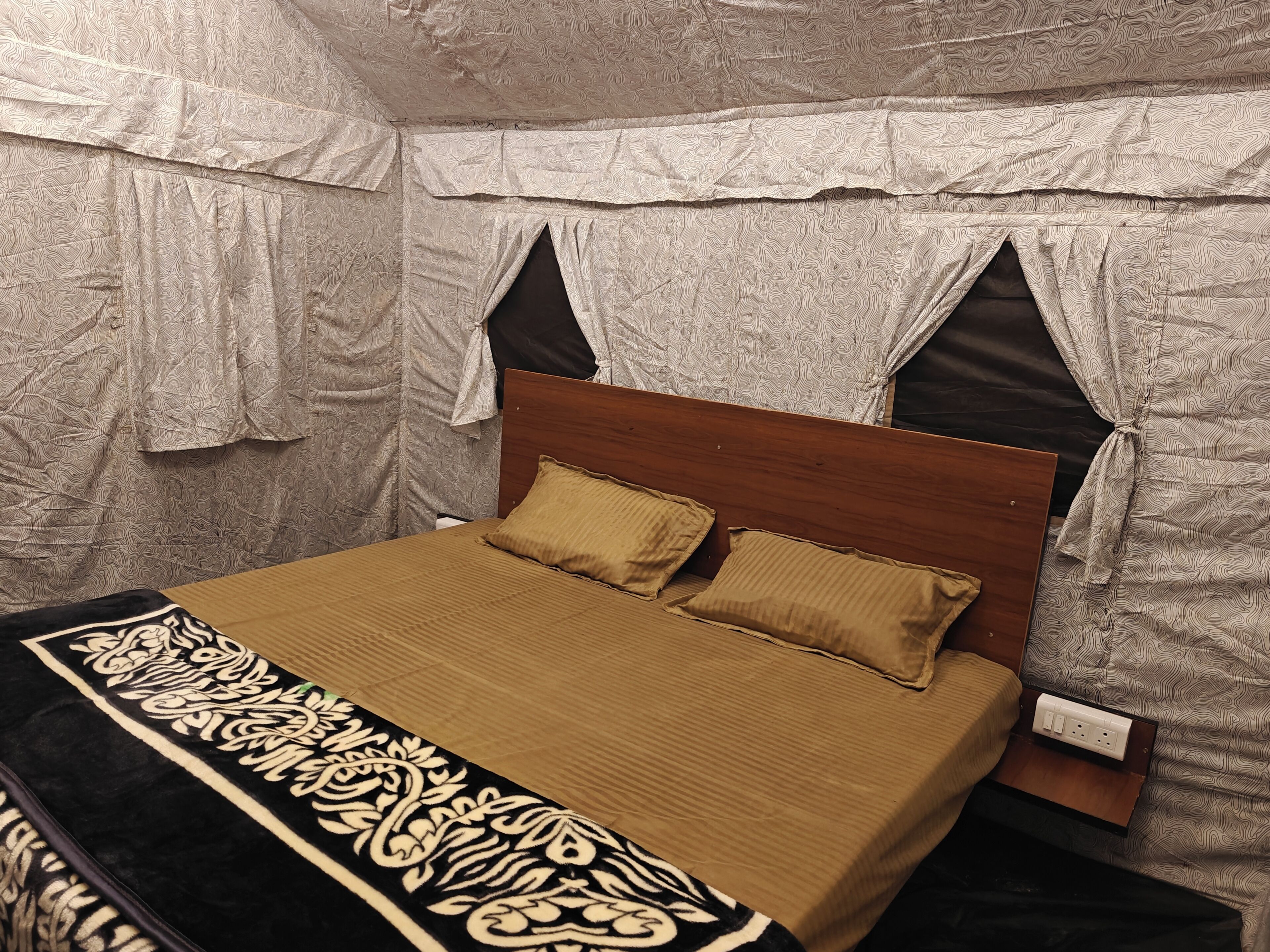 A single bed with a wooden headboard, two pillows, and a patterned bedspread.