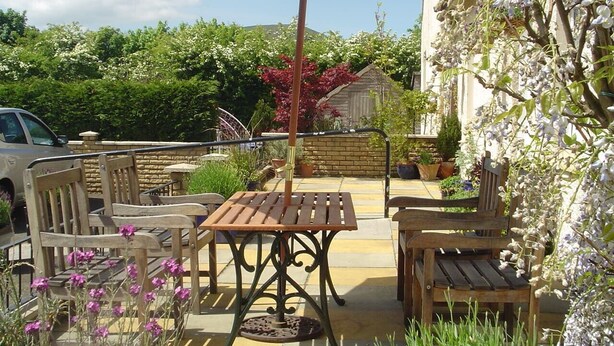 An outdoor patio with wooden furniture, a table, and an umbrella.