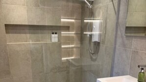 Un bagno moderno con doccia a filo pavimento, un lavandino bianco e uno specchio sopra.