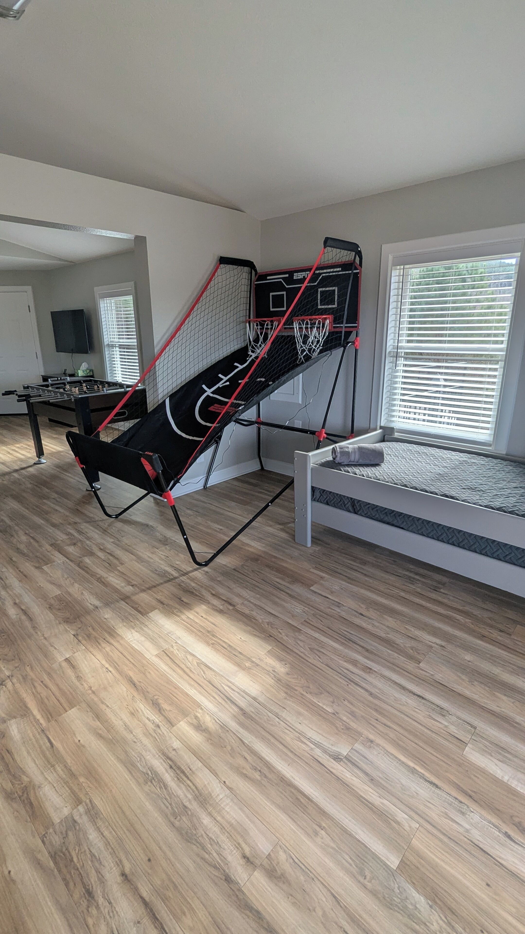 A room with a futsal court, a bed, a window with blinds, and a television.