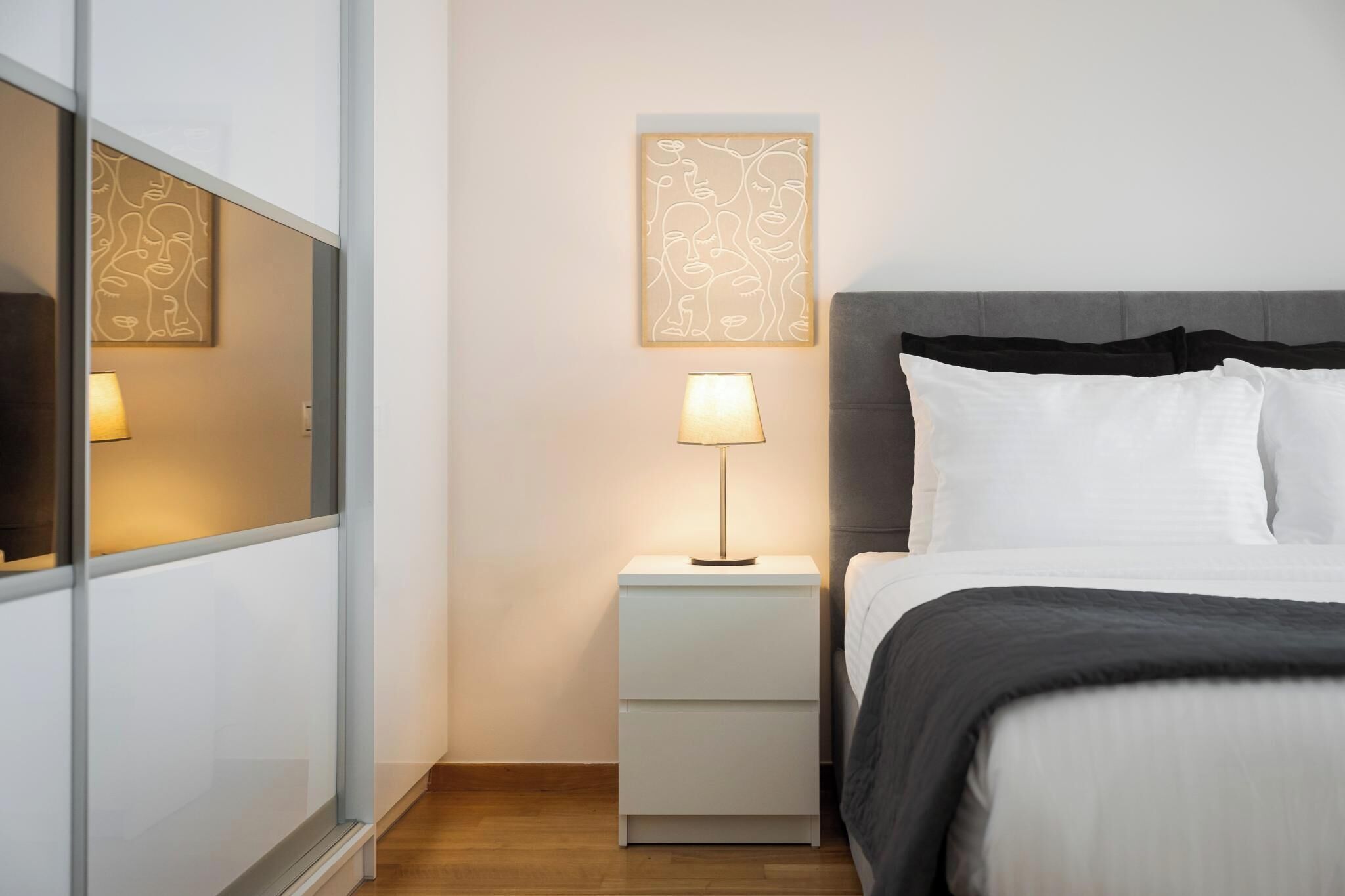 Un dormitorio ordenado con cama, mesitas de noche y decoración en la pared.