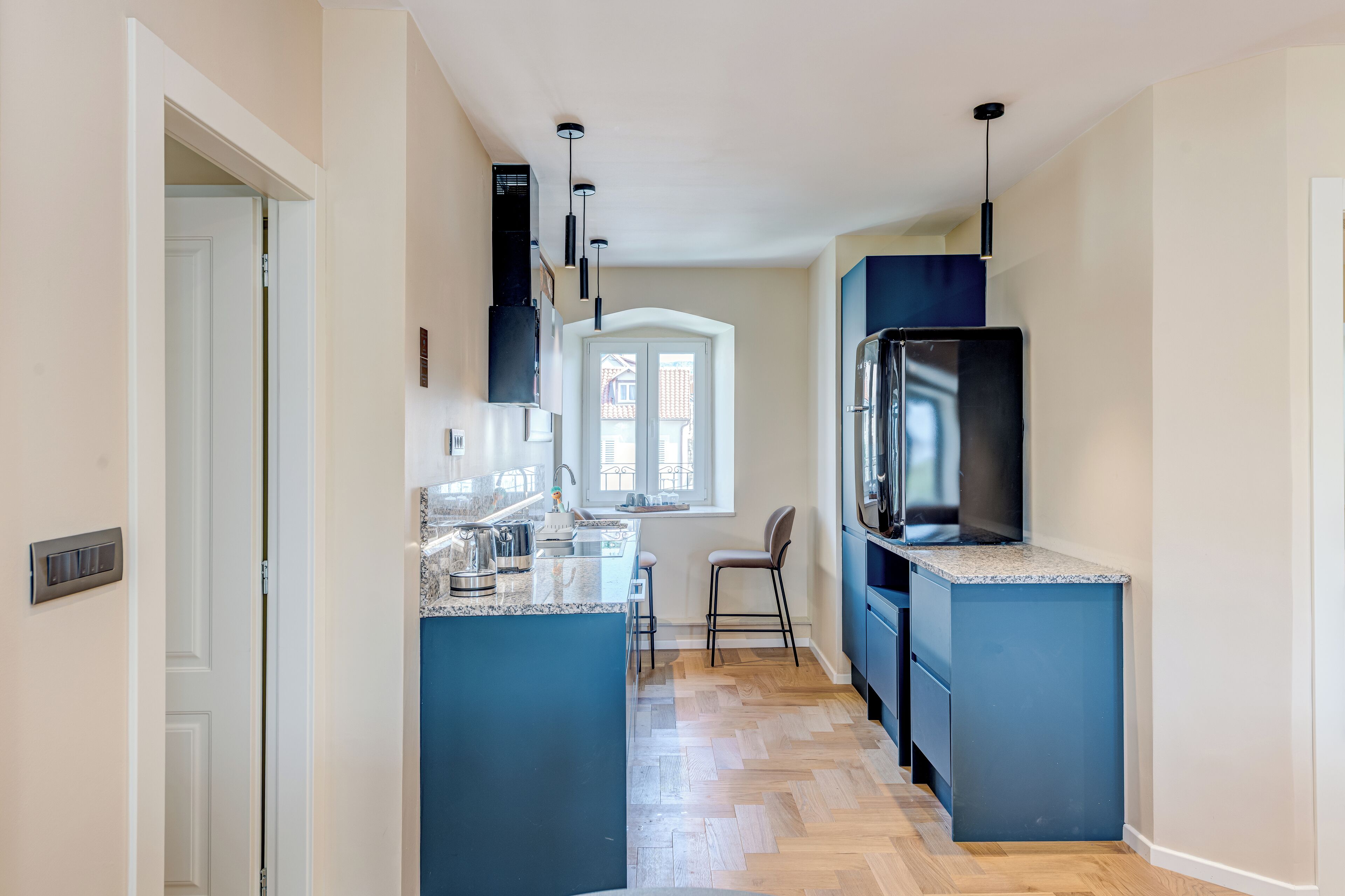 Eine moderne Küche mit blauen Schränken, einer eingebauten Kochinsel und einem großen Kühlschrank.