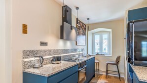A modern kitchen with granite countertops, a built-in oven, and a stainless steel refrigerator.