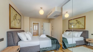A bedroom with two beds, a wooden nightstand, a mirror, and artwork on the walls.