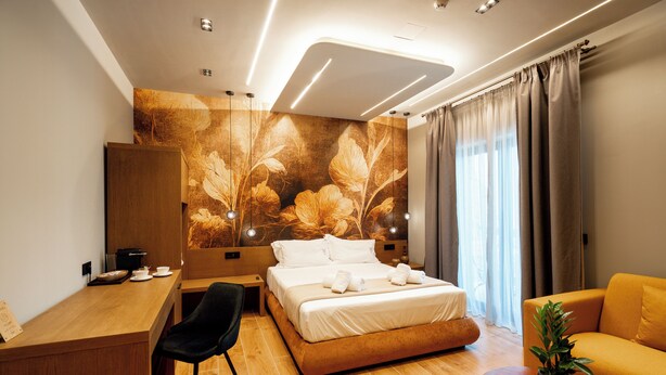 A hotel room with a bed, desk, chair, and a sofa. - Ode Aristofanous - Urban Hotel (Athens)