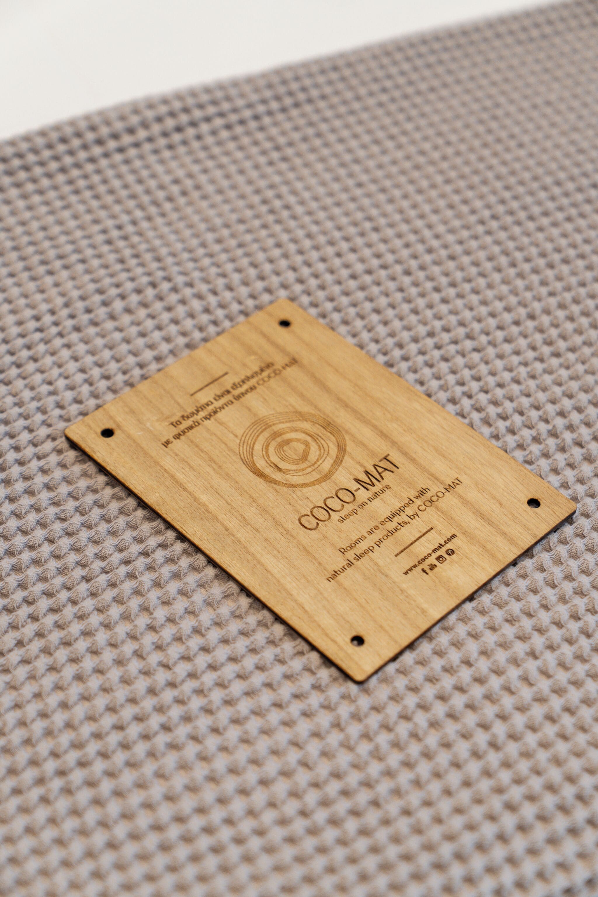 A wooden plaque with text and a circular design, placed on a textured surface.