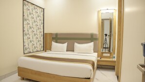 Ein Hotelzimmer mit einem Bett, einem großen Spiegel, einem Holzkopfende, einer gerahmten Blumenblume und einem Marmorboden.