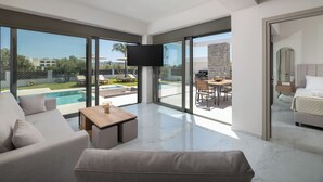 Ein modernes Wohnzimmer mit großem Fenster, Flachbildfernseher und Blick auf einen Pool.