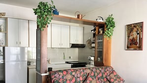 Een woonkamer met een bloemenbank, een houten salontafel en een keuken op de achtergrond.