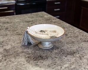 Una ciotola con interno bianco e bordo decorativo, posata su un piano di granito.
