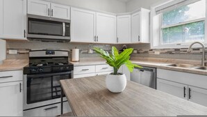 A modern kitchen with white cabinets, a stainless steel stove, a microwave, and a sink. - King bed Crystal Lake Mchenry Cary Cozy (Cary)