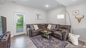 A modern living room with a sectional sofa, a coffee table, a floor lamp, and a bull's head wall decoration. - King bed Crystal Lake Mchenry Cary Cozy (Cary)