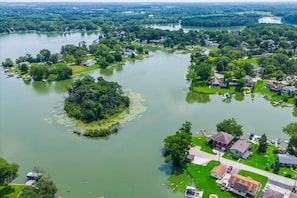 An aerial view of a lakeside community with houses, boats, and greenery.