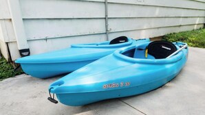 Two kayaks with the text 'aruba 8 35' on them, placed on a concrete surface in front of a building. - Steps to the Lake- Cozy 2 Bedroom Retreat (Bristol)