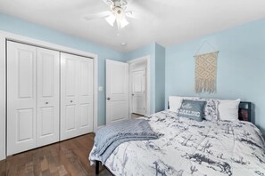 Un dormitorio con cama, ventilador de techo y un adorno macramé en la pared.