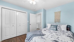 A bedroom with a bed, a ceiling fan, and a wall-mounted macrame piece. - Steps to the Lake- Cozy 2 Bedroom Retreat (Bristol)