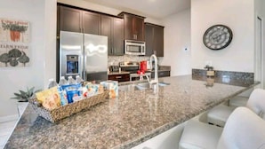A modern kitchen with granite countertops, stainless steel appliances, and dark wooden cabinets. - Free Amenities Spacious Home King Beds (Kissimmee)