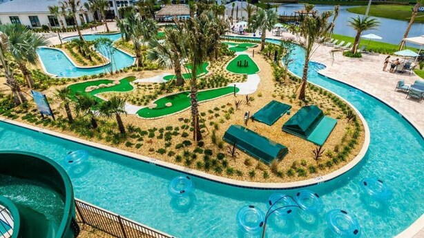 A resort pool area with multiple swimming pools, palm trees, and a view of the water body. - Free Amenities Spacious Home King Beds (Kissimmee)
