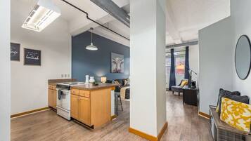 Un apartamento moderno con cocina equipada, que incluye estufa y lavaplatos, zona de comedor con mesa y sillas, y sala de estar con sofá y mesa de centro.