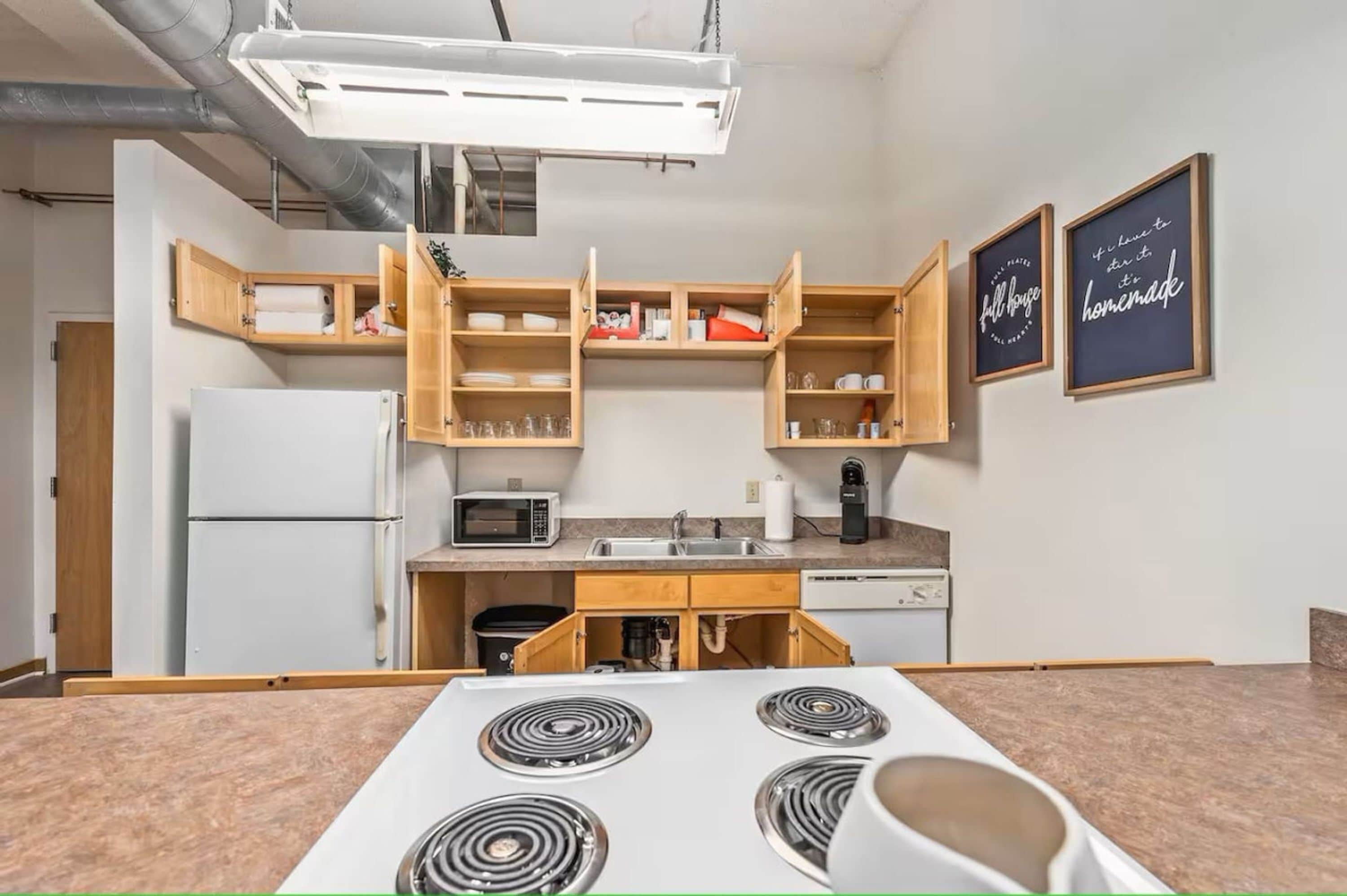 A compact kitchen with built-in appliances, wooden cabinets, and a microwave.