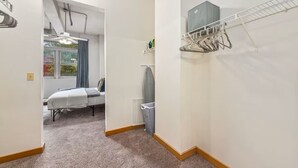 Ein schmaler Flur mit einem Bett im Hintergrund, einem Wäscheständer und einer Heizung.