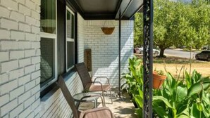 Une terrasse couverte avec un mur en briques, un panneau d’accueil et des sièges d’extérieur.