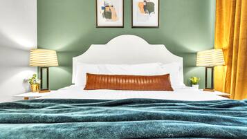 A neatly made bed with a white headboard, two bedside lamps, and a teal blanket.