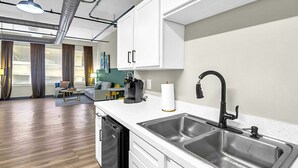 Una cocina moderna con armarios blancos, fregaderos de acero inoxidable y un grifo negro.