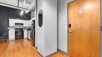 A modern kitchen with white cabinets, a built-in oven, and a wooden floor.