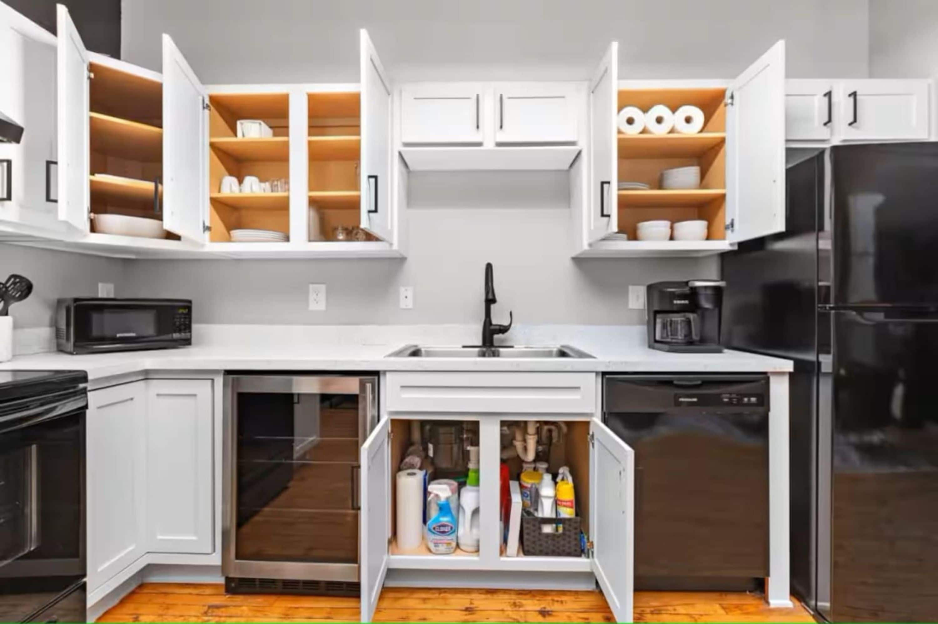 A compact kitchen with white cabinets, a black refrigerator, and a built-in dishwasher.
