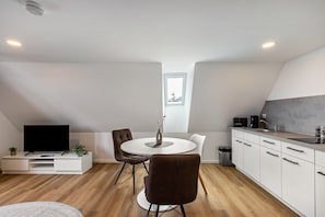 A modern kitchen with a dining area, a TV, and a window.