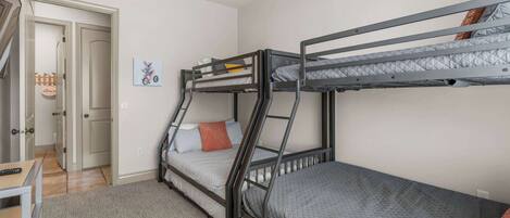 A room with bunk beds, a desk, and a ceiling fan.