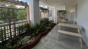 A covered patio area with a table and benches, surrounded by plants and a wooden fence. - Calm and Green Place (Chiang Mai)