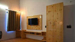 Une pièce avec une armoire en bois, un téléviseur fixé au mur et un banc en bois.