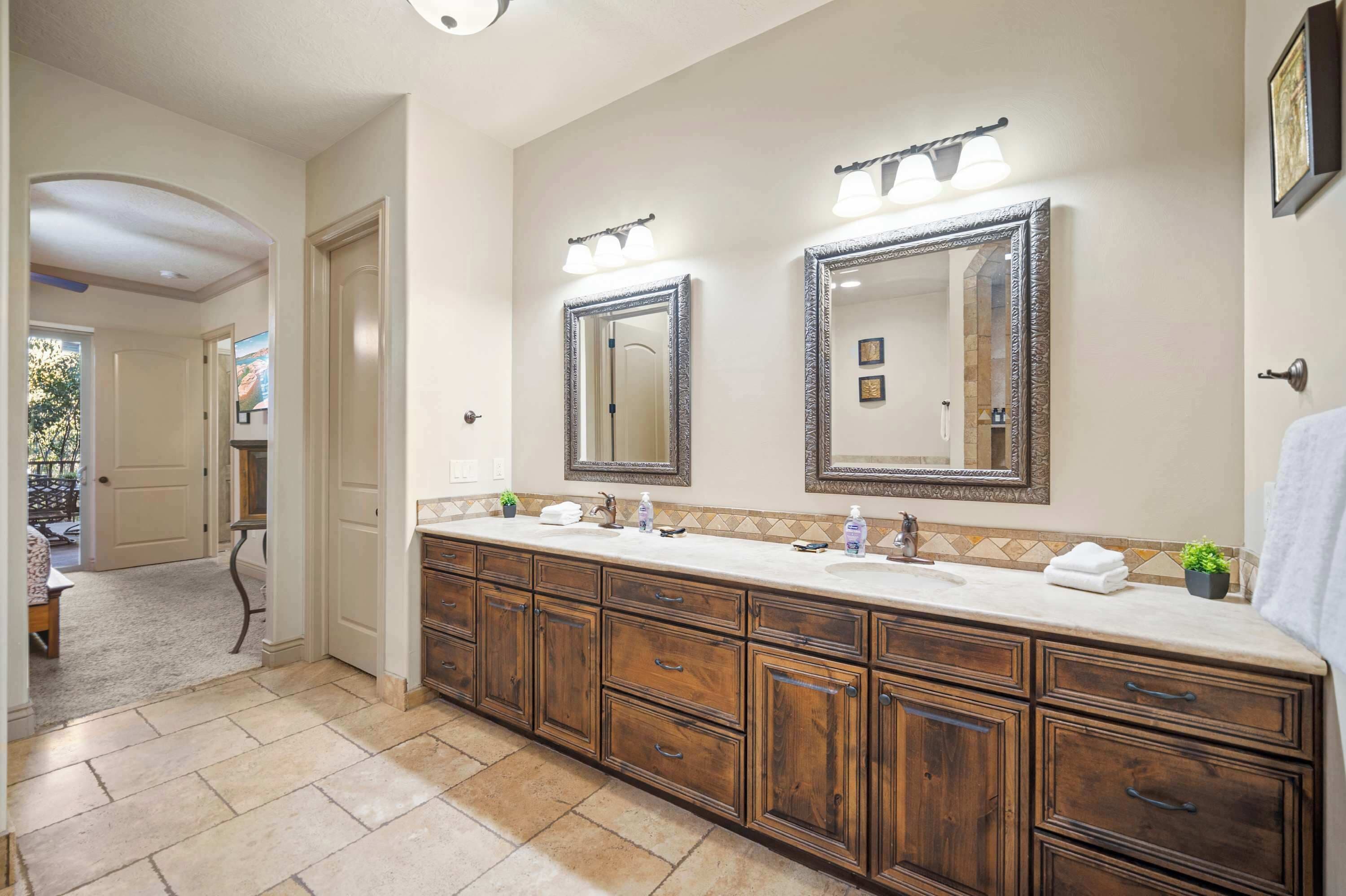 A spacious bathroom with a large vanity, double mirrors, and a tiled floor.