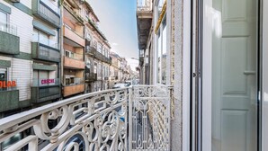 A narrow street with ornate metal railings, buildings with balconies, and a visible shop sign.