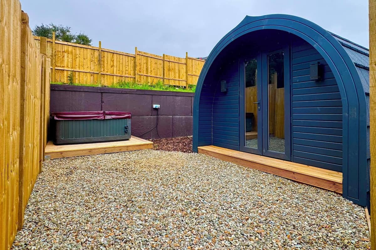 Un espace aménagé comme un spa, avec un jacuzzi, une terrasse en bois et une structure bleue aux lignes courbes.