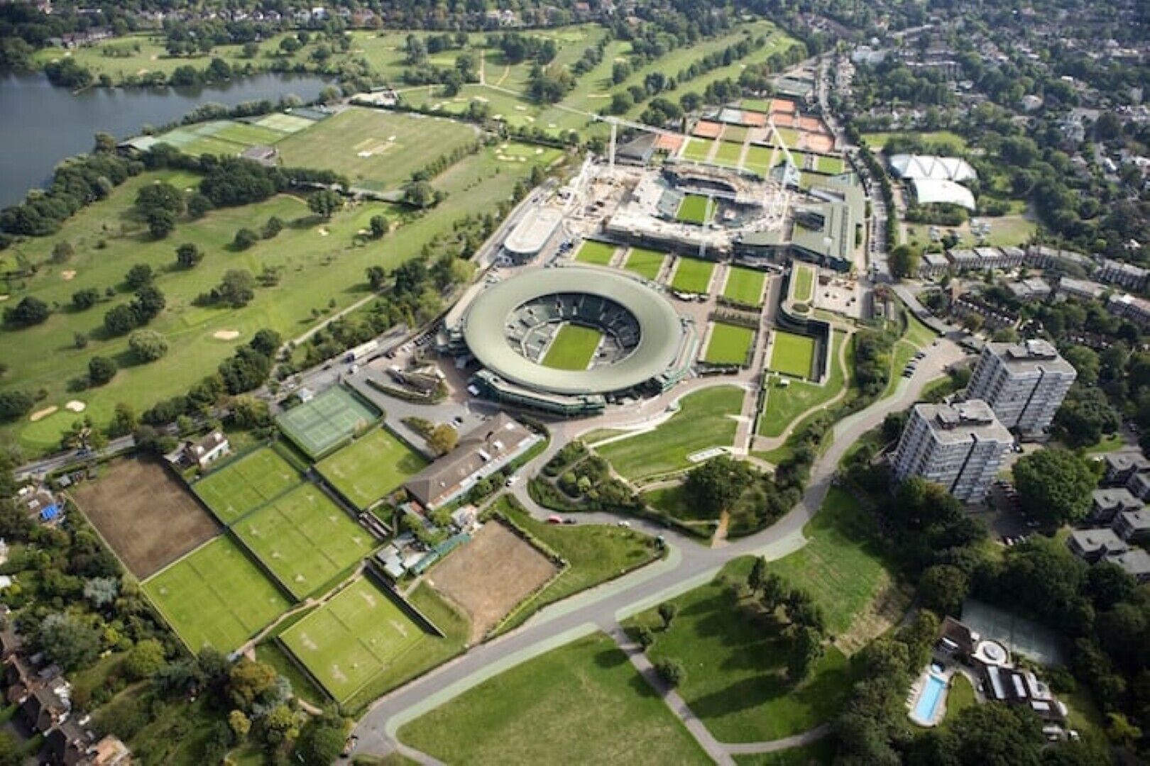 Luchtbeeld van een sportcomplex met een groot stadion, verschillende sportvelden en woongebouwen.